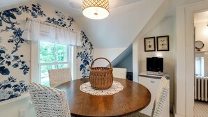 A dining area with a round wooden table, white wicker chairs, a woven basket, and a ceiling light fixture. - On-Site Pond: Spacious Family Home in Jefferson! (Jefferson)