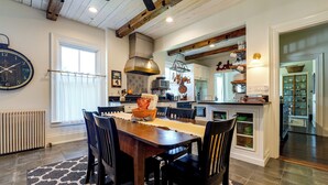 A modern kitchen with a dining area, featuring a wooden table, chairs, and a large clock on the wall.
