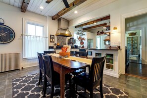 A modern kitchen with a dining area, featuring a wooden table, chairs, and a large clock on the wall.