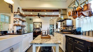 A modern kitchen with white cabinetry, a marble countertop, and copper cookware hanging above. - On-Site Pond: Spacious Family Home in Jefferson! (Jefferson)