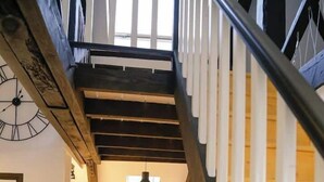 Un escalier en bois mène à une cuisine équipée d’une table et de chaises.