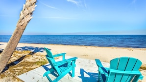 A beach with turquoise chairs and a palm tree.