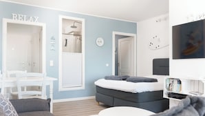 A modern bedroom with a bed, a small table, and a seating area. - Vacation apartment Meerblickbude (Wendtorf)