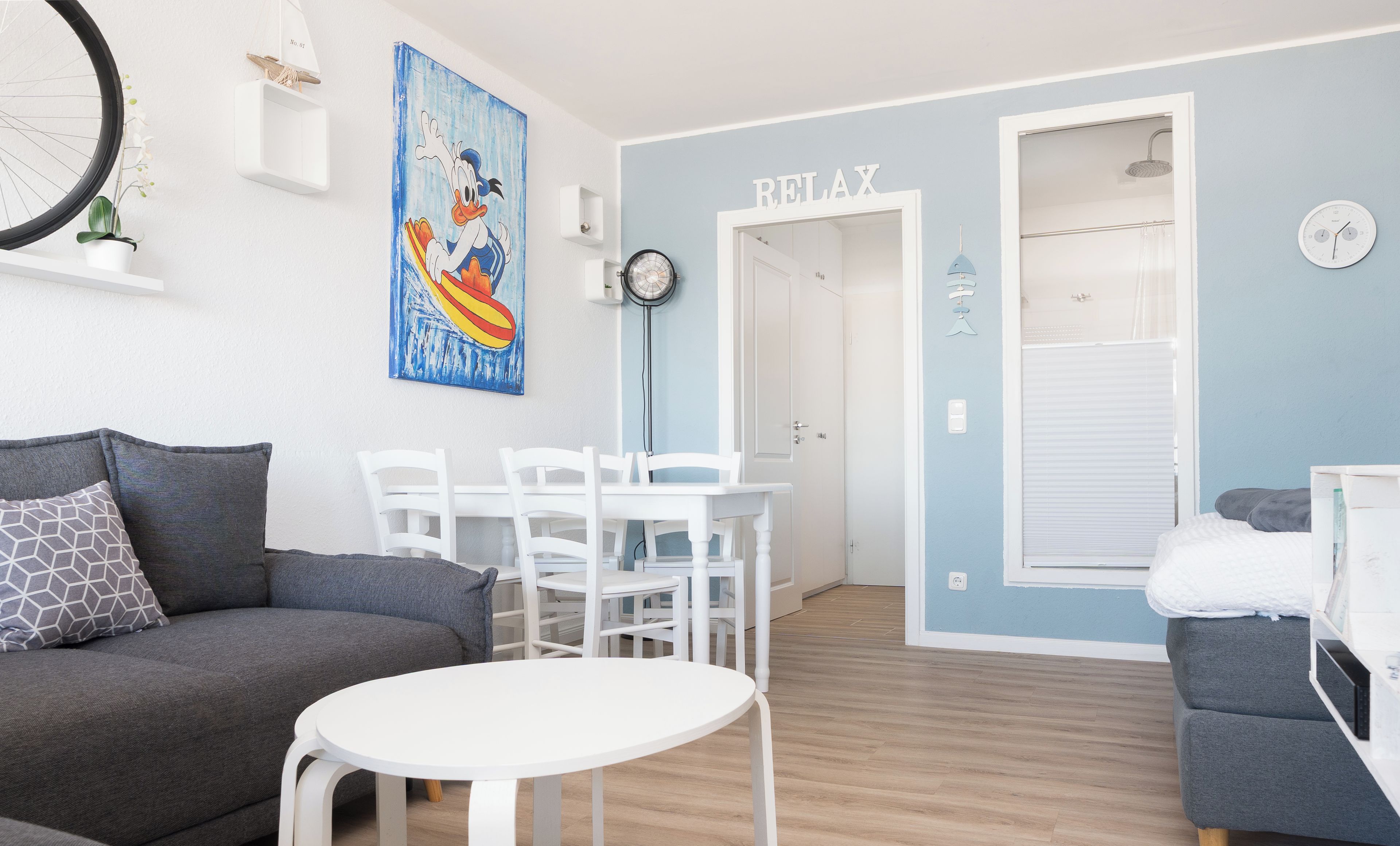 Un saló modern amb un sofà gris, una taula rodona blanca i una paret d'accent blau.
