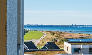 A view of a coastal area with a golf course, a body of water, and buildings in the foreground.