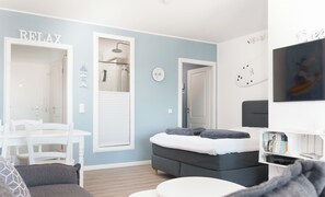 A modern bedroom with a bed, a small table, and a seating area.