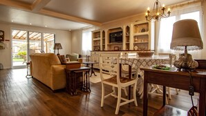 A spacious living area with a sofa, dining table, and chairs. There is a kitchen area with a TV and cabinets. - Casa da Porta Amarela - Holiday Home in the Seven Cities (Ponta Delgada)