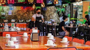 A restaurant with wooden tables and red chairs, a stone wall, and colorful decorations. - Hotel Casa Kolping (Tuxtla Gutierrez)