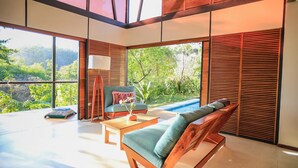 Un interior moderno con un ventanal grande, un banco de madera, una mesa y una silla.
