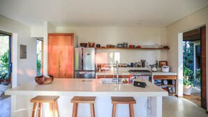 Una cocina moderna con una isla grande, taburetes de madera y varios utensilios de cocina en estantes.