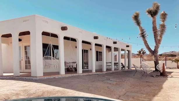 A modern building with a pool, outdoor seating, and a desert landscape. - Luxe Desert Retreat: Hot Tub, Cowboy Pool & Outdoor Shower (Yucca Valley)