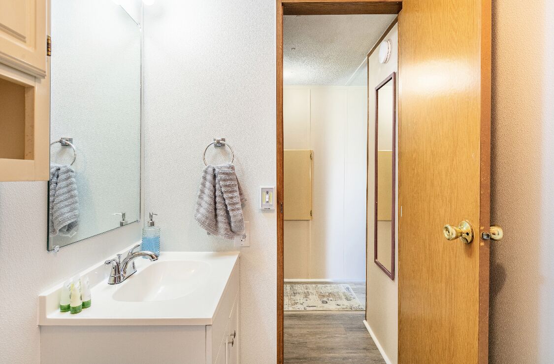 Un baño con un lavabo blanco, dos toallas y un espejo.