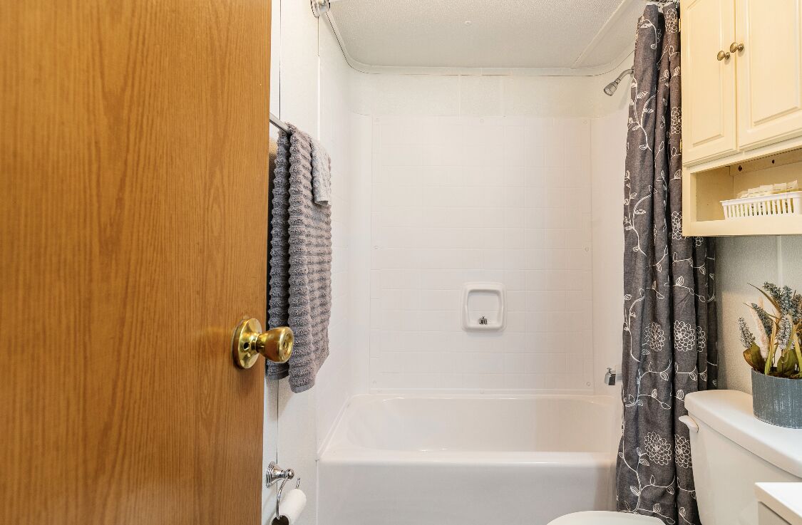 Ein Badezimmer mit Badewanne, Toilette und einer Holztür.