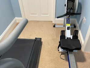 Un gimnasio en casa con cinta de correr, bicicleta estática y equipo de ejercicio.