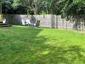 A backyard with a wooden fence, a table, and chairs.