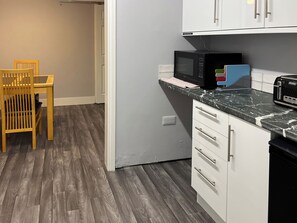 Una cocina con microondas, tostadora y una silla de madera.