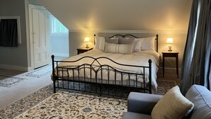 A bedroom with a bed, two bedside tables with lamps, a ceiling fan, a window, and a door. - Independence Inn (Strafford)