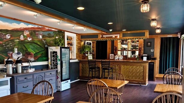A restaurant with wooden tables and chairs, a bar area, and a mural on the wall. - Independence Inn (Strafford)