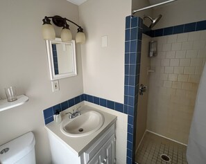 A bathroom with a sink, mirror, and shower. - Independence Inn (Strafford)