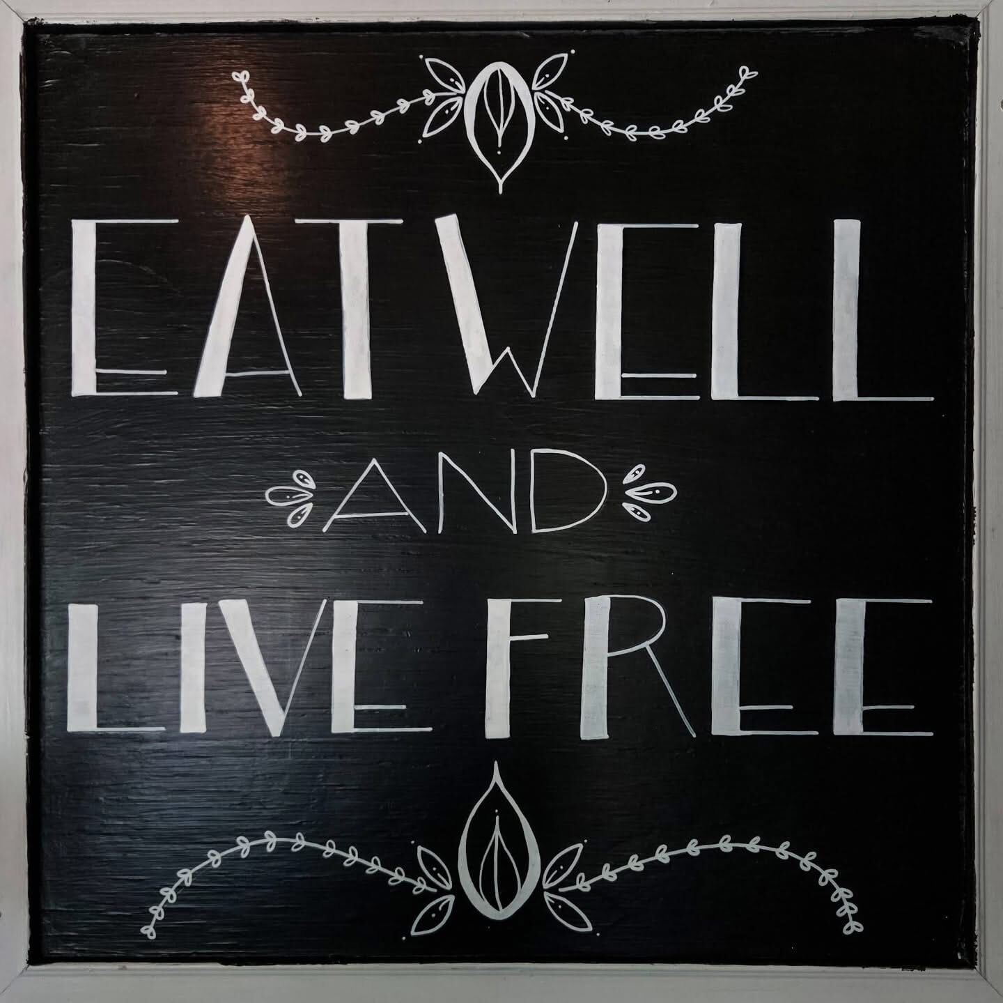 A blackboard with white text that reads "EATWELL AND LIVE FREE."