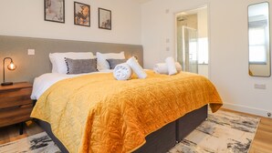 Une chambre d’hôtel moderne avec un grand lit, une table de chevet, une commode, un miroir et un espace douche.