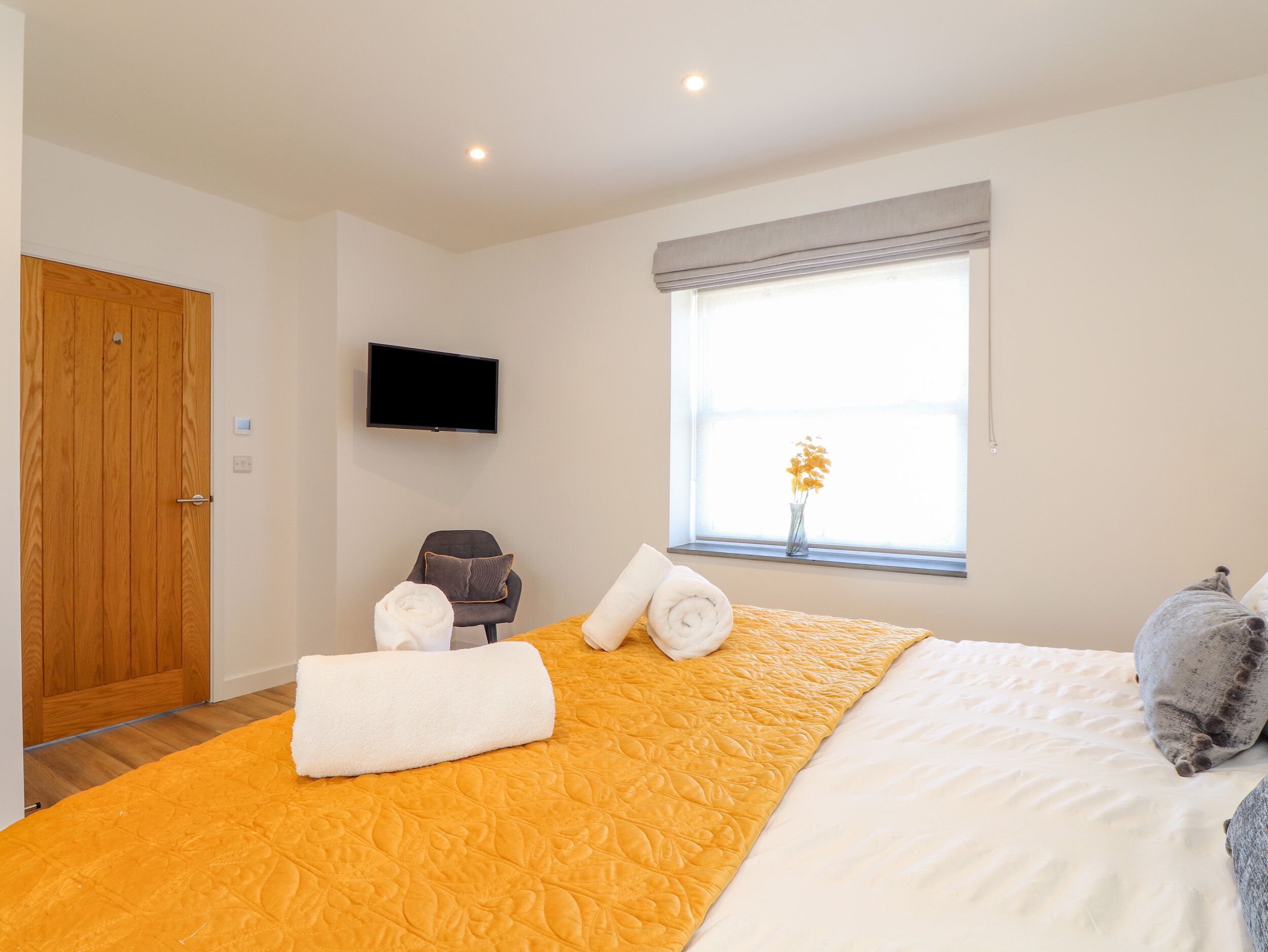 A hotel room with a bed, a chair, a TV, and a window with a view.