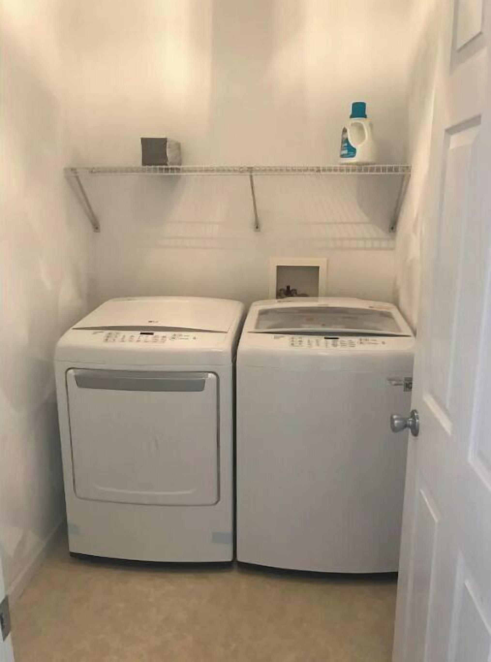 Une buanderie avec deux machines à laver blanches et une étagère au-dessus.