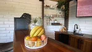 A kitchen with a fruit basket on the counter, a microwave, a sink, and a glass shelf with decorative items. - Tranquil country setting w/majestic views (Escondido)