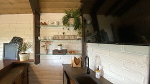 A kitchen with white brick walls, a wooden ceiling, and shelves with various items including plants, a coffee sign, and kitchenware. - Tranquil country setting w/majestic views (Escondido)