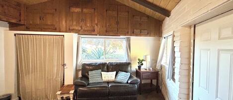 A cozy living room with a leather sofa, a small table, and a window with curtains.
