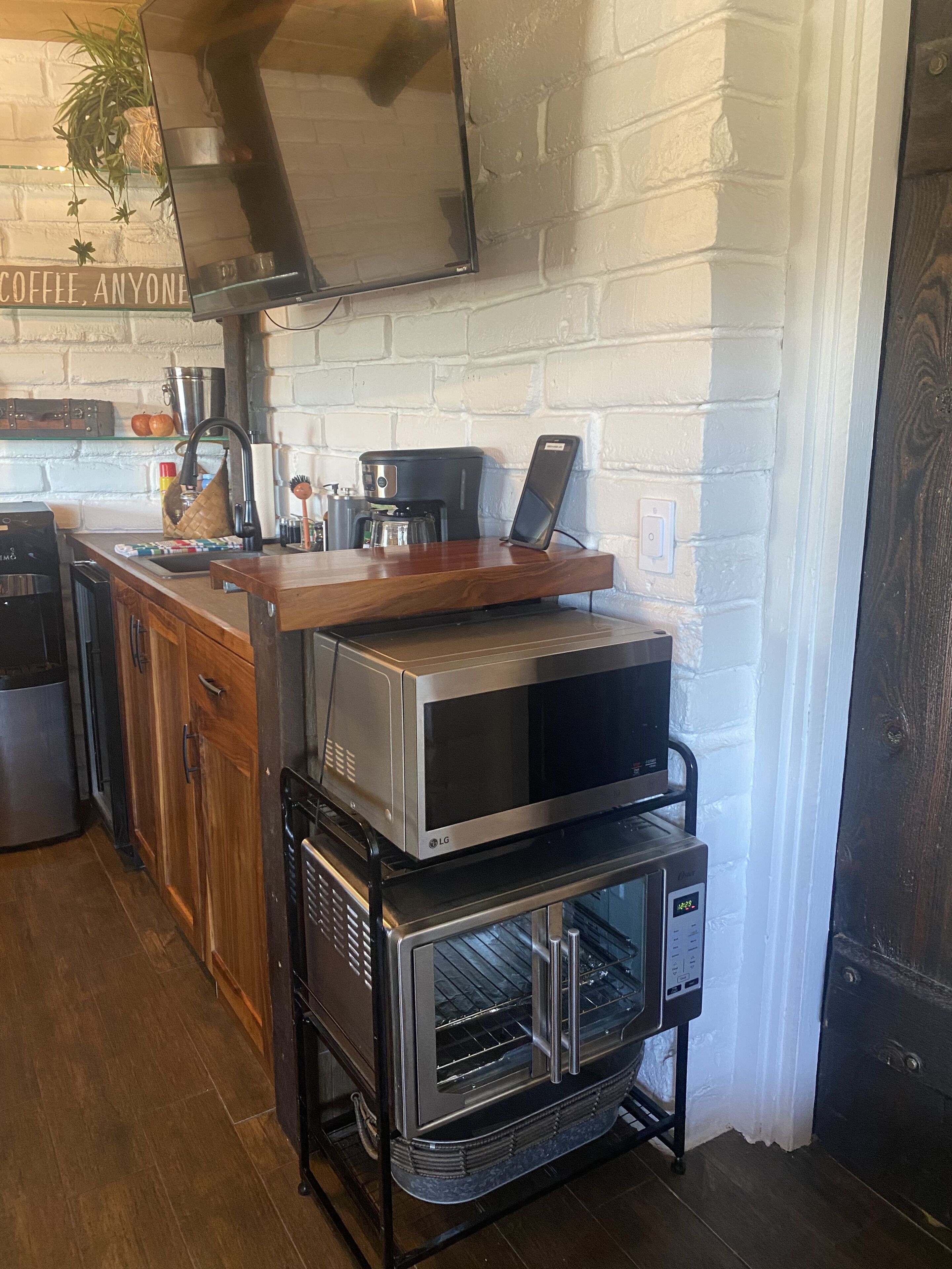 A kitchen with a microwave, oven, and coffee machine on a countertop.