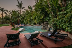 A poolside area with lounge chairs and a small pool surrounded by tropical plants. - Luxury Retreat-Pool/HotTub/Game Room/Putting Green (Escondido)