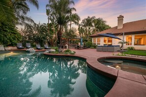 A pool area with lounge chairs, a gazebo, and a house with a tiled roof. - Luxury Retreat-Pool/HotTub/Game Room/Putting Green (Escondido)