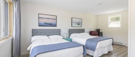 A hotel room with two beds, a window, and a view of the sea.