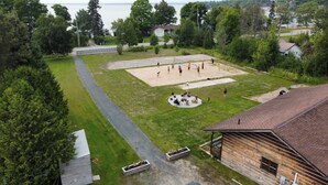 Zona residencial con un campo cubierto de césped, una cabaña de madera y vistas a un lago.