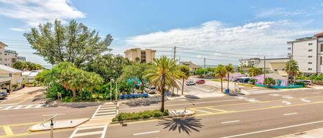 A street view with a crosswalk, palm trees, and buildings.