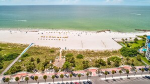 Un resort frente a la playa con una amplia extensión de arena, zona de estacionamiento y un edificio de hotel.