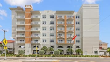 A multi-story hotel with balconies, a pedestrian crossing sign, and a flag.