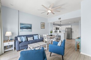 A modern living room with a sofa, chairs, a coffee table, and a ceiling fan.