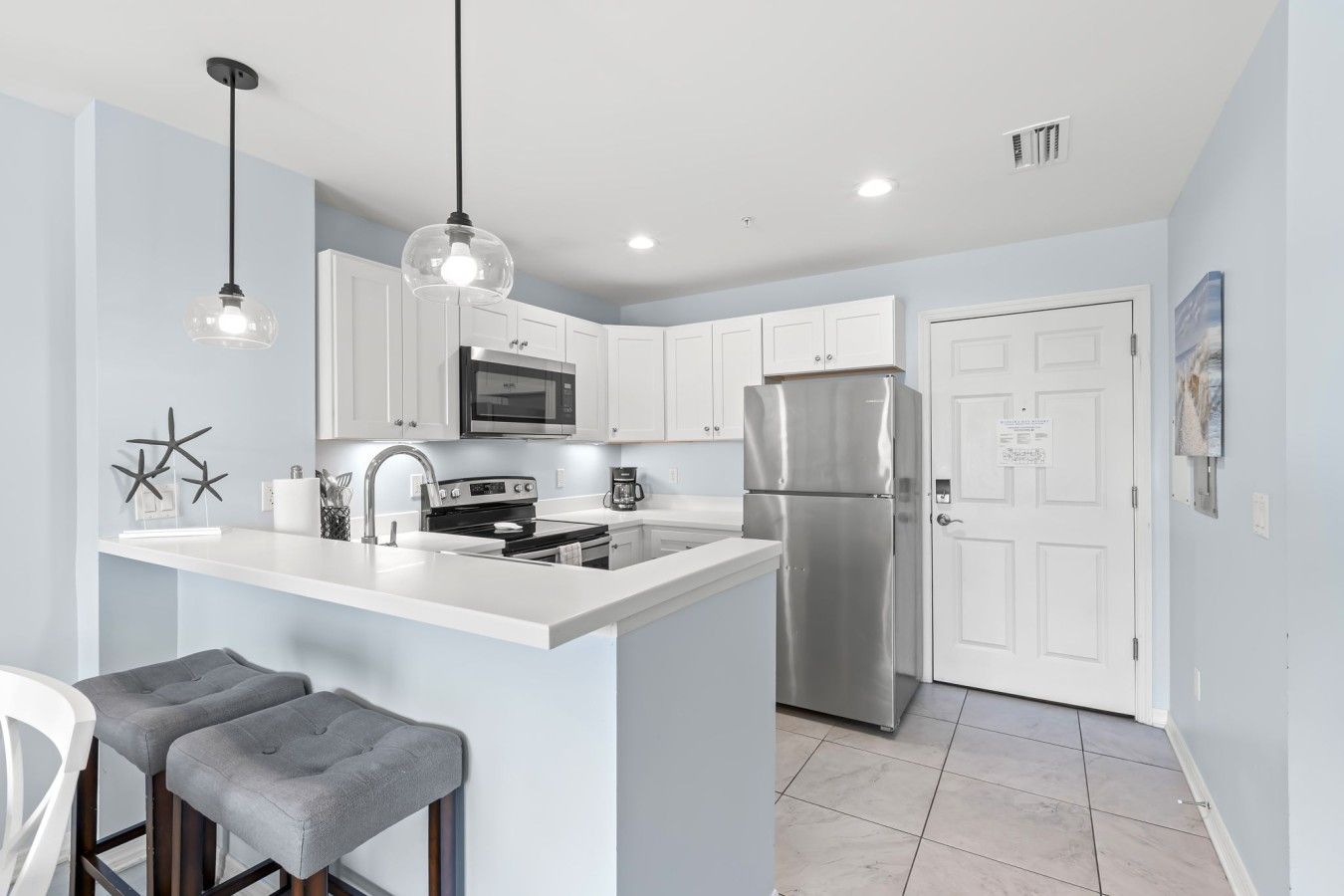A modern kitchen with a central island, stainless steel appliances, and pendant lighting.
