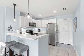 A modern kitchen with a central island, stainless steel appliances, and pendant lighting.