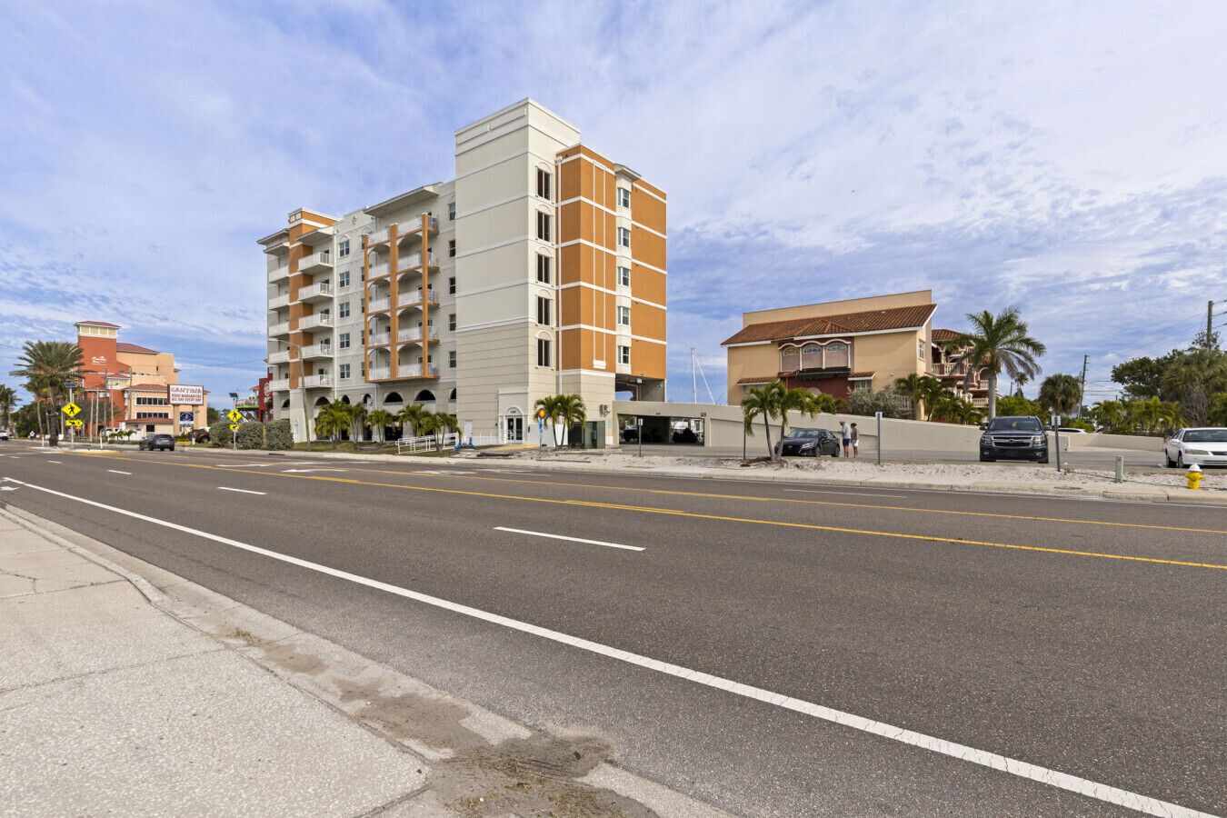 A multi-story hotel with balconies, a parking area, and a clear sky.