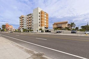 A multi-story hotel with balconies, a parking area, and a clear sky. - Coastal Retreat in Madeira Beach/Johns Pass (Madeira Beach)