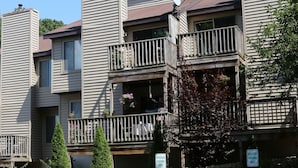 A multi-story residential building with balconies, a stone facade, and a sign indicating reserved parking.