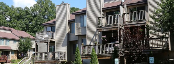 A multi-story residential building with balconies, a stone facade, and a sign indicating reserved parking.