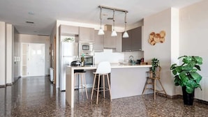 A modern kitchen with a central island, bar stools, and a potted plant. - Modern flat with sea views in Valencia. (Valencia)