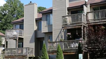 Un immeuble résidentiel à plusieurs étages, doté de balcons, d’une façade en pierre et d’un panneau indiquant les places de stationnement réservées.