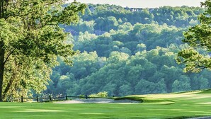 Un campo de golf con un fairway bien cuidado, bunkers de arena y una bandera que marca el hoyo.