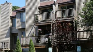 Un edificio residencial de varios pisos con balcones, fachada de piedra y un letrero que indica estacionamiento reservado.