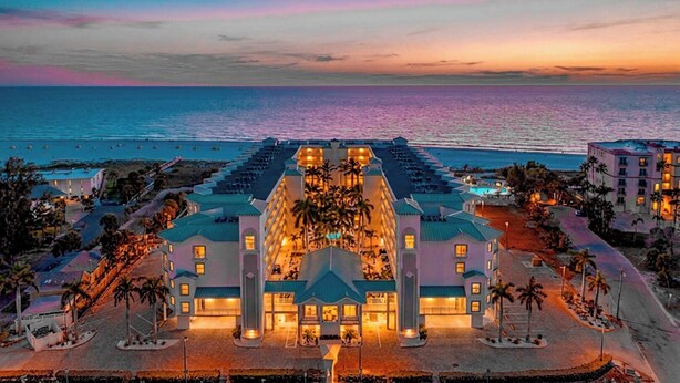 Ein Resort mit einem zentralen Gebäude, mehreren Balkonen und Blick aufs Meer.